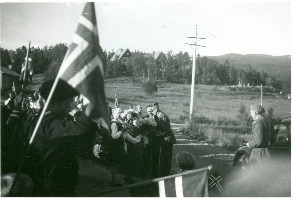 Kong Haakons besøk på Drevjamoen i 1946. Oberst A.Hauge til høyre. Offisersmessa i bakgrunnen.