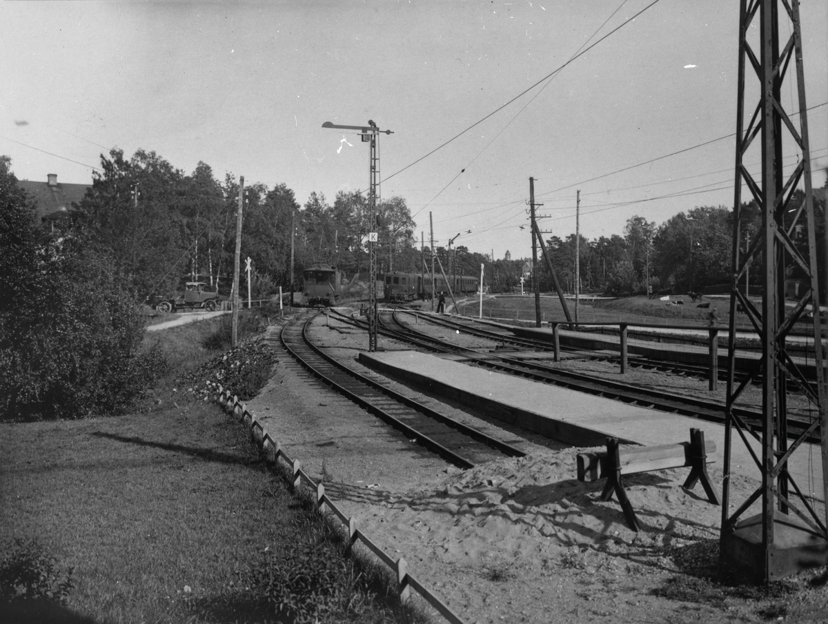 Perrong och bangård vid Djursholms Ösby järnvägsstation. Stationen öppnades 1890 av Djursholms Aktiebolag och var en del av Djursholmsbanan som då sträckte sig mellan Djursholms Ösby och Djursholms Framnäsviken. 1892 togs linjen över av Stockholm-Rimbo Järnvägsaktiebolag, och blev så småningom en del av Roslagsbanan.

Till vänster står SRJ Mv 2 och till höger syns SRJ Mv ur serie 7-14.

Motorvagn; Vägmärke; Kryssmärke: Personal