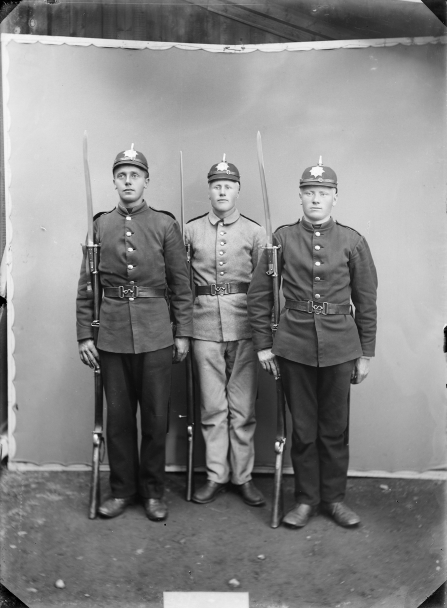 3 soldater fra Bjorli/Lesjaskog med gevær, bajonett og hjelm model 1891. Den lyse uniformen er infateriets våpenfrakk modell 1888. De mørke uniformene er antatt modell 1894 for sanitetskorpset. Antatt sted Jørstadmoen, Fåberg.