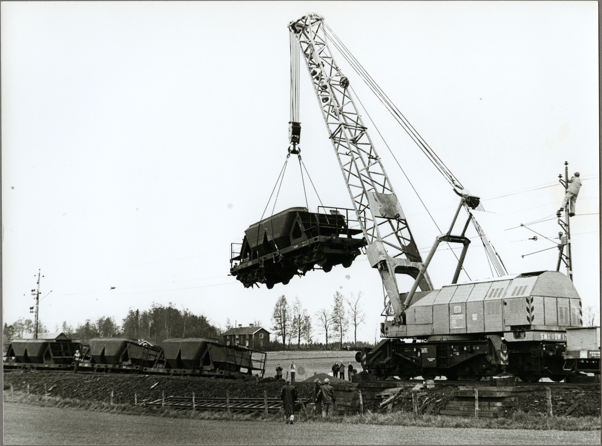 En kranvagn tillverkad av Schwermaschinenbau SM Kirow med littera Statens Järnvägar, SJ Qan lyfter en urspårad malmvagn.