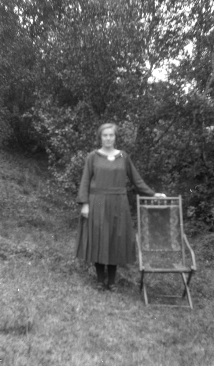 Kvinne stående med stol utendørs.