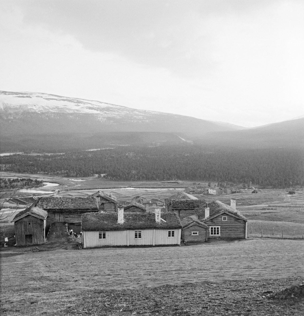 Utsikt mot Lordalen fra hovedvegen (i dag E136) gjennom den nordre delen av Lesja mot Romsdalen. I forgrunnen ser vi garden Ljosbakken i Bjøknegrenda. Til høyre i nedenfor ligger garden Ekren. Lesjaleirene med Lågen i bakgrunnen.