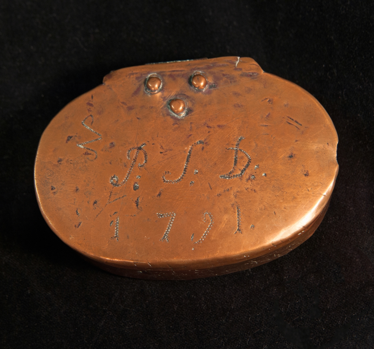 En oval tobaksdosa av koppar. Förtennat inuti. På locket tremblerade initialer och årtal: "P:S:D: 1791".