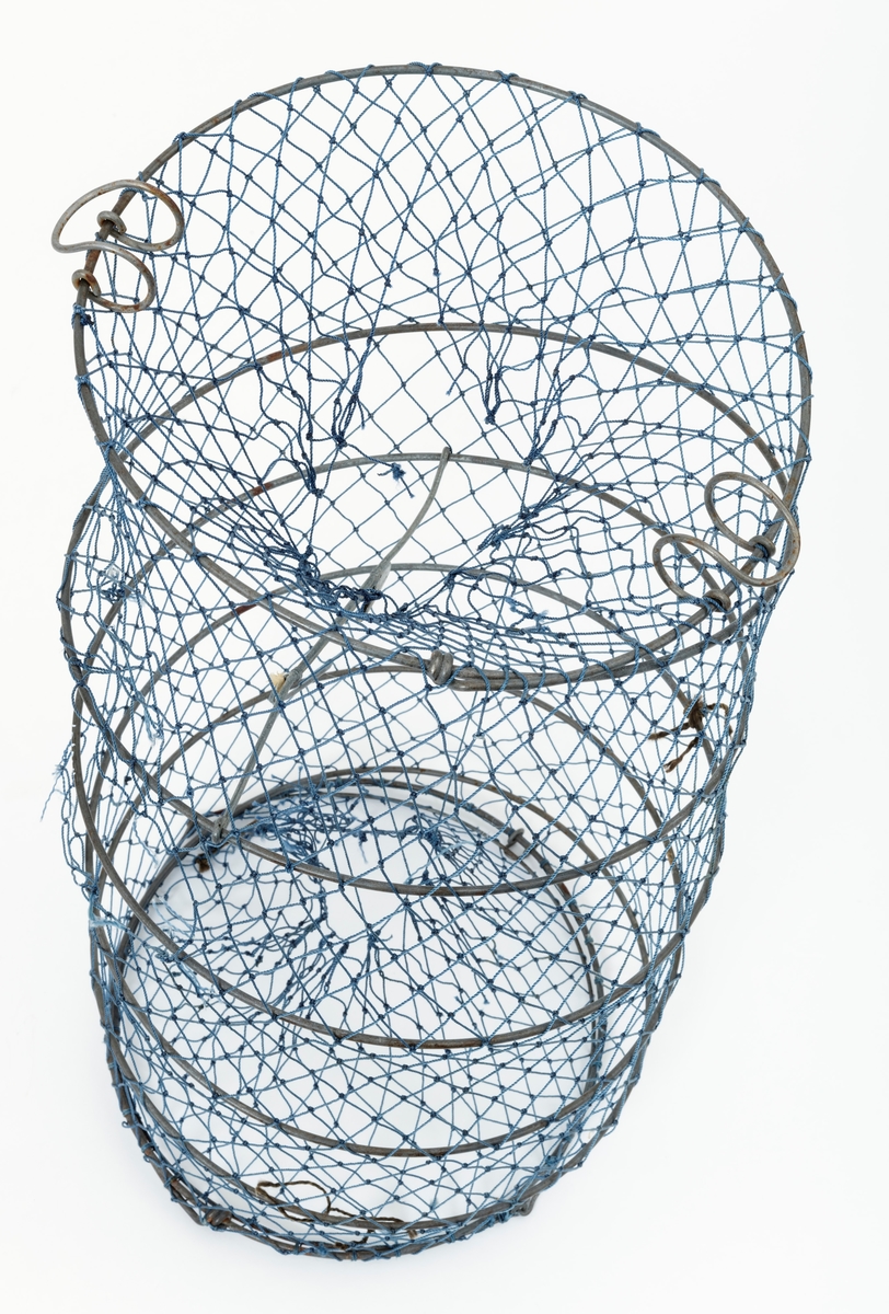 Krepseteine med stamme, spiral, i galvanisert metalltråd dekket av blå netting, garn, av nylon (trolig) med agnholder. Spiralen, stammen, er sammenleggbar, holdes sammen med klemmer. Teina har inngang i begge ender. Åpningene er kjegleformet, traktformet, inn til et rom der krepsen søker etter agnet som er festet til en agnholder. Agnholderen er utformet som en stor sikkerhetsnål.