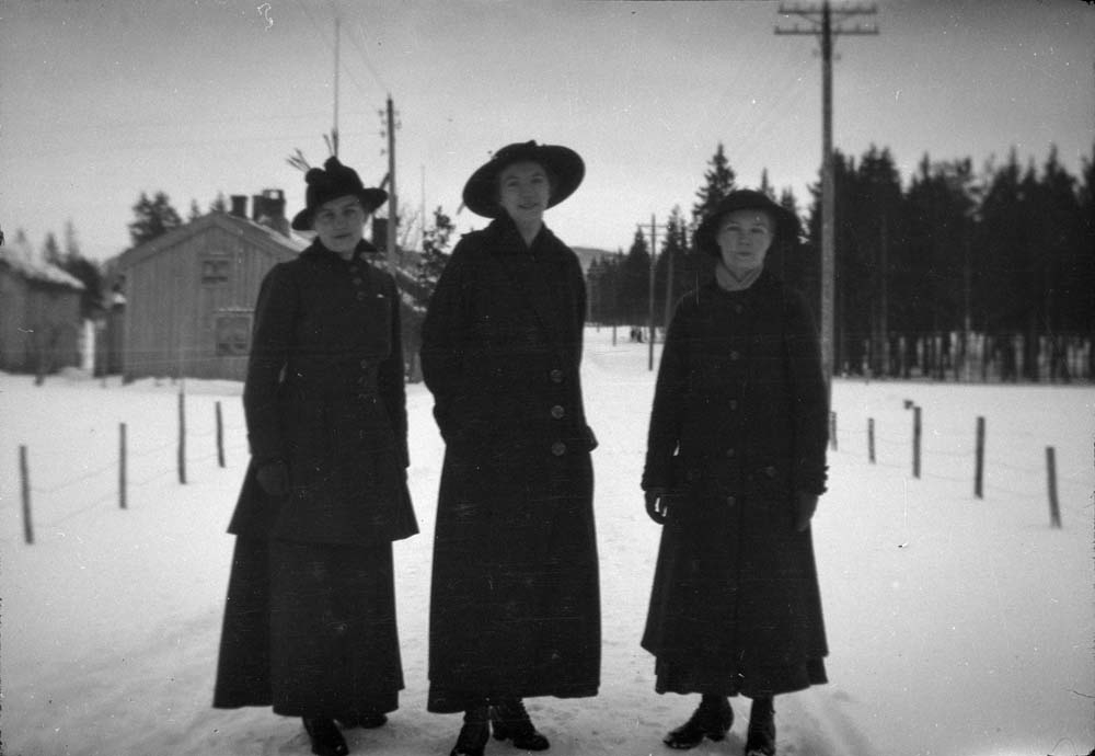 Tre kvinner som står i snøfylt gate.