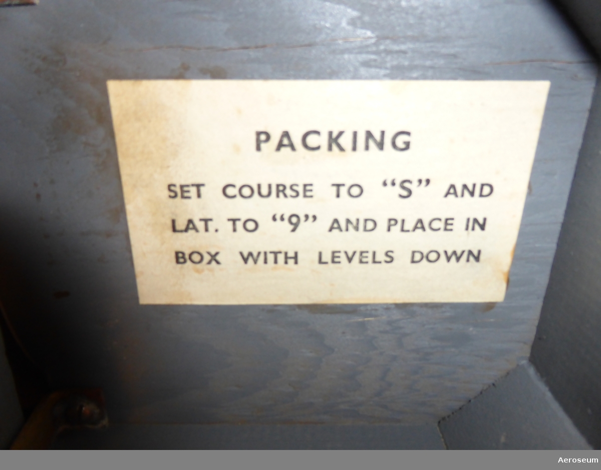 en Astrokompass i en grå trälåda. Serienummer är 11592. På lådan går det att läsa "ASTRO COMPASS MKII". På locket, lådans framsida och baksida står det med röda bokstäver och vit bakgrund "DELICATE INSTRUMENT TO BE HANDLED WITH GREAT CARE".

På insidan av locket finns det en stämpel som ger årtalet 1944 och en papperslapp där det står: "PACKING" och "SET COURSE TO "S" AND LAT. TO "9" AND PLACE IN BOX WITH LEVELS DOWN".