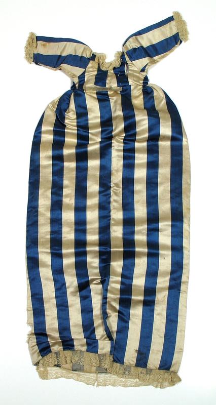 Dåpskjole i stoff med brede blå og hvite striper med blonder rund nedkant, ermer og halsringing. Dåpskjolen er båret i begynnelsen av 1800-årene.