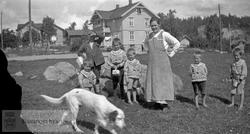 Kvinne, barn og hund på gårdstun