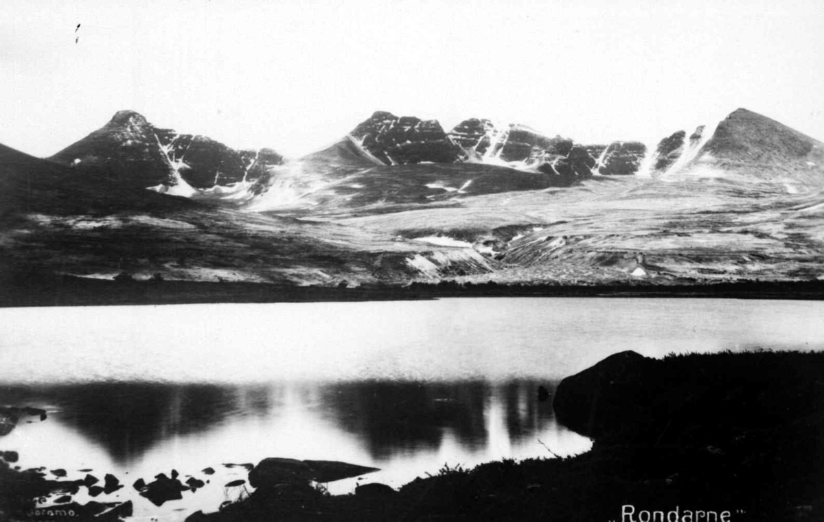 Repro etter postkort av Hans H. Joramo: Rondane med Neverbutjønnet foran og fra venstre, Høgronden Midtronden og Digerronden bak.
