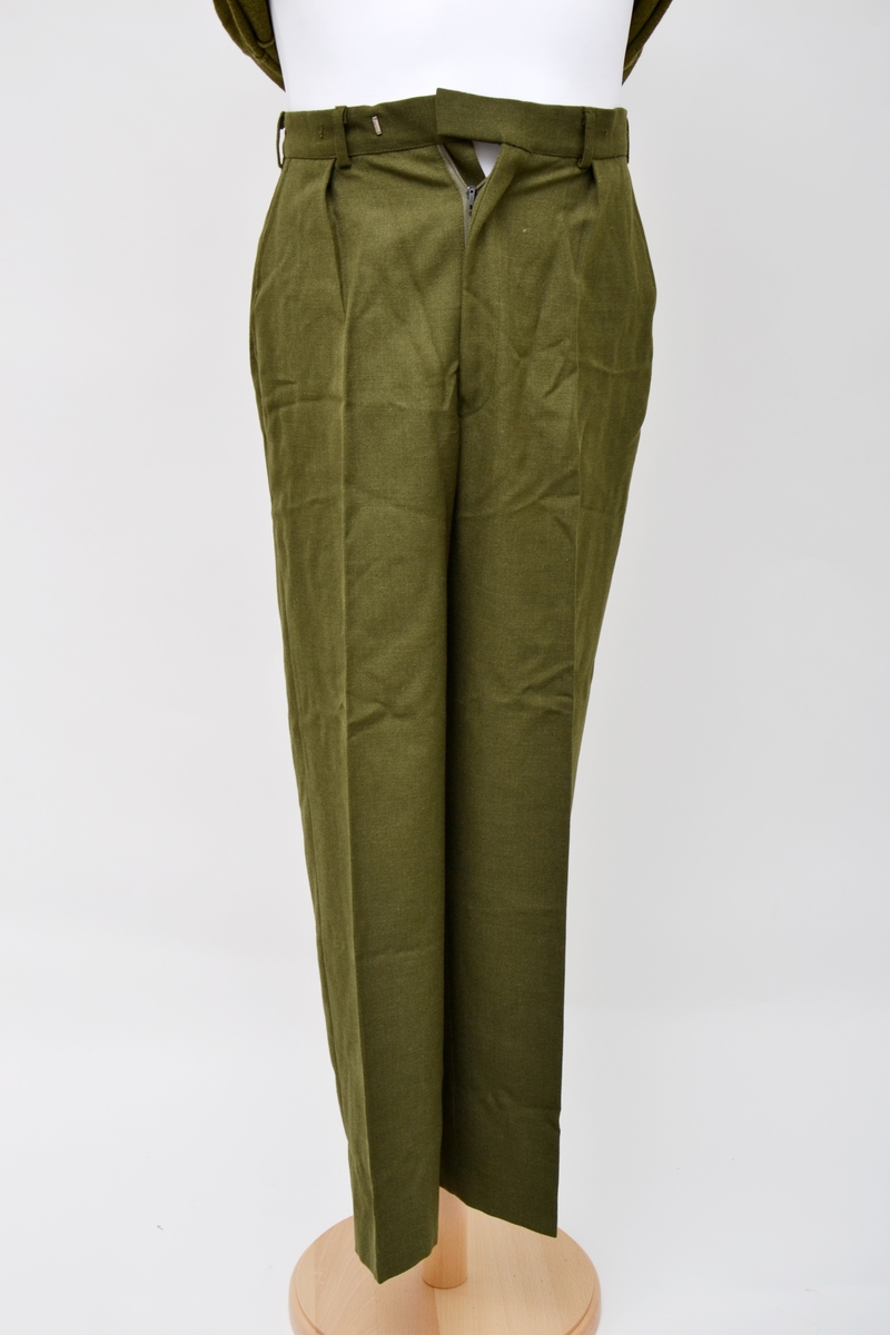 Grønn uniformsbukse i ull med to stikklommer i front og to baklommer med klaffer. Lukkes med glidelås og metallhemper. Tre plastknapper bak til å fest i hemper på uniformsjakken.