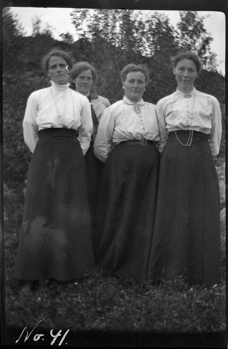 Gruppeportrett av fire kvinner, fotografert stående utendørs.