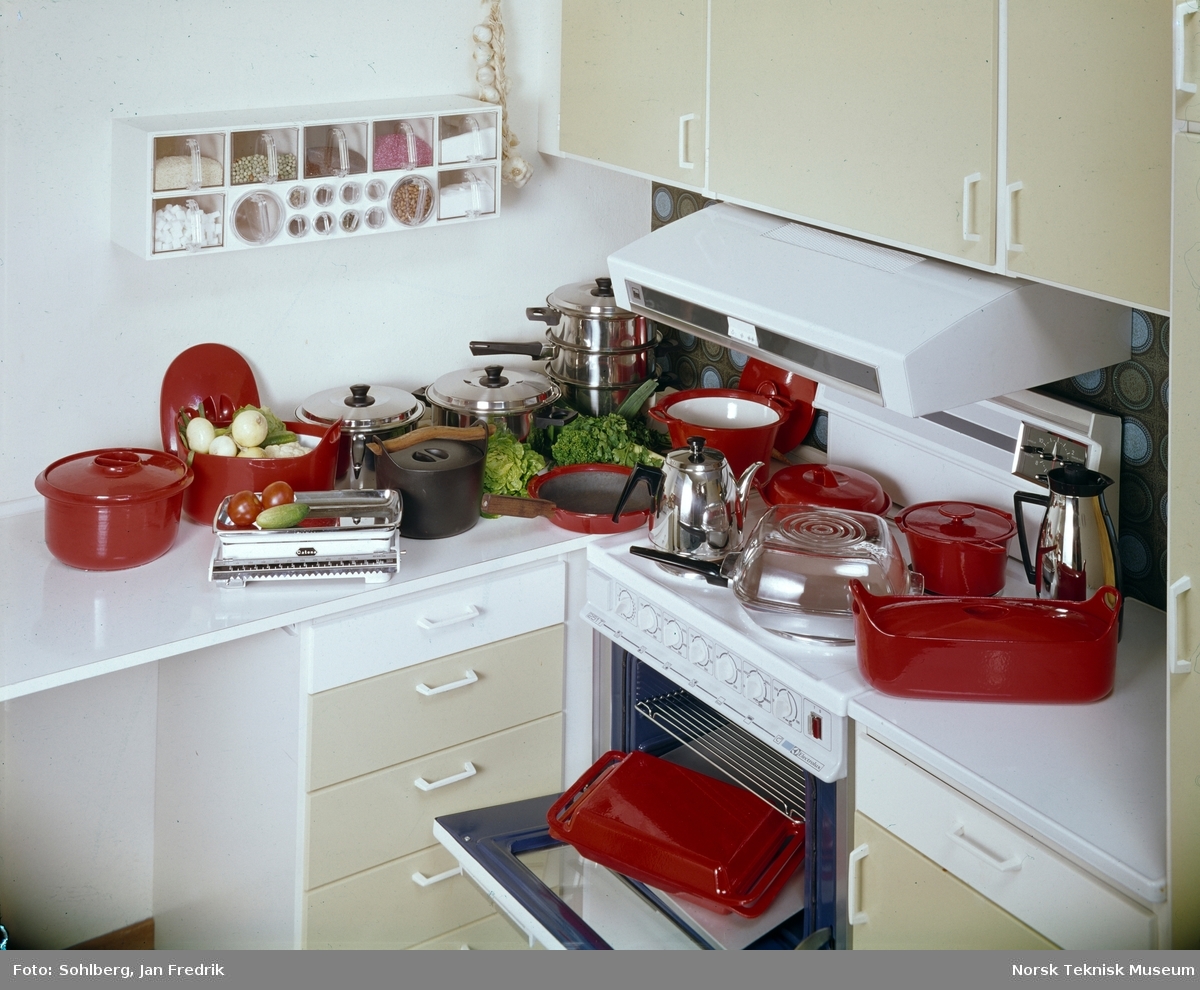 Et velutrustet kjøkken med diverse kjøkkenutstyr; røde og blanke kjeler, kasseroller, panner, kanner og fat.