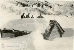 Fire menn på taket av ei snødekt seterbu