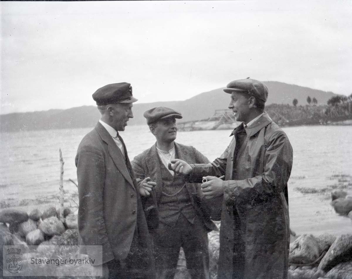 Tre menn diskuterer ved sjøen..Oscar Iversen til venstre (?)