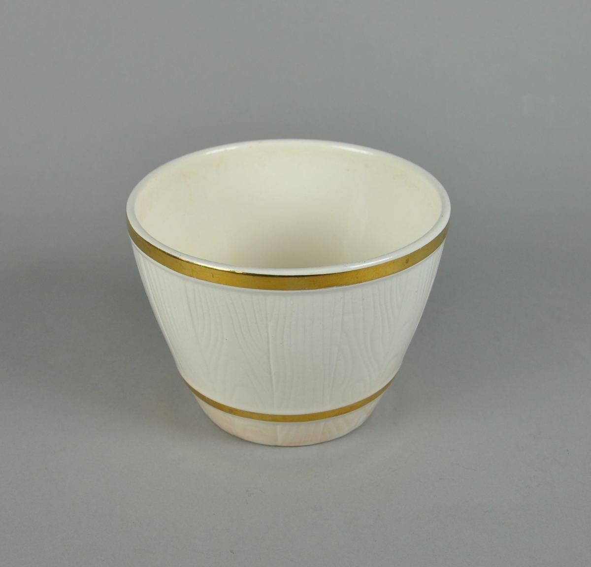 Blomsterurne av hvit keramikk. Urnen har to gullmalte linjer.