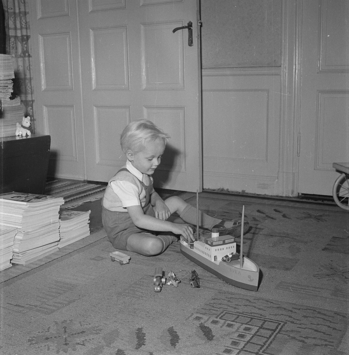 Pojke sitter på golvet och leker med båt, Uppsala 1954