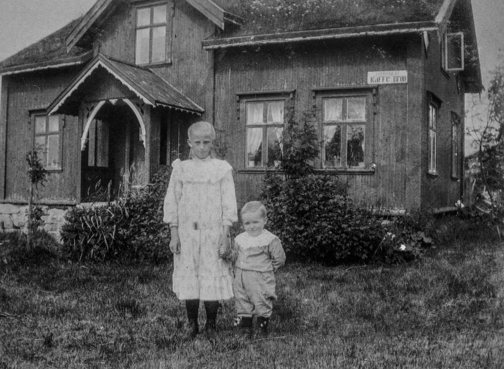 Leirfjord, Leland, Breivika. Fotografering utenfor huset til jordmor Marie Leland. Foran huset er datteren til Marie, Ragna Leland f. Olsen og en liten gutt (ukjent).