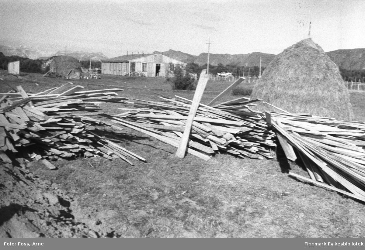 I Tana, i mai-juni 1947. Muligens Finnmarkskontorets brakke i bagrunnen, i forgrunnen ligger masse planker.
