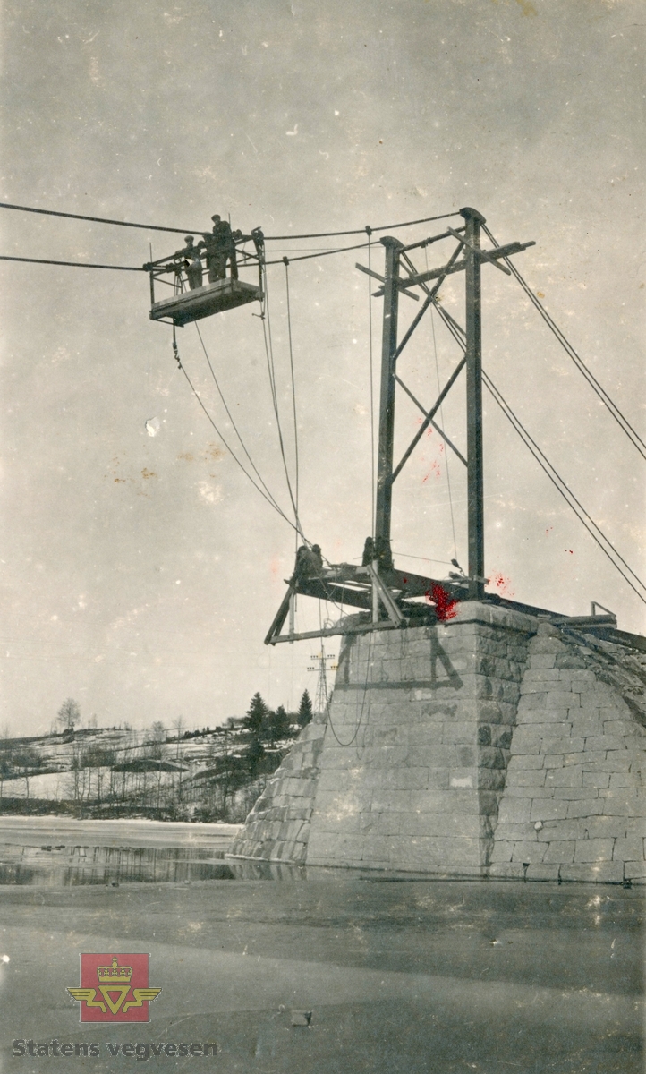 Eikernsundet bru over sundet mellom Eikeren og Fiskumvannet i Øvre Eiker. Kabelferje over sundet fram til 1924 da Eikernsundet hengebru stod ferdig. Bildet viser montering av hengestenger fra hovekablene.