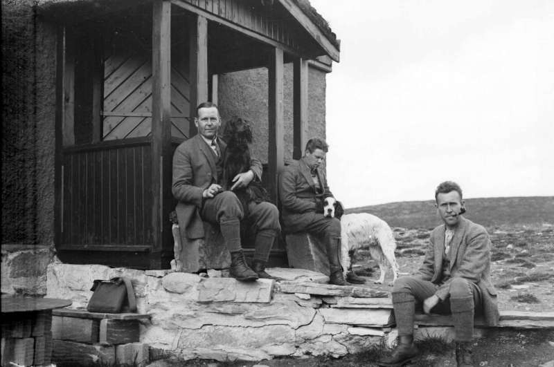 Tre menn framfor «Hygga» ved Flaksjøen i Ringebu. Anders Andersson  i midten, øvrige ukjente