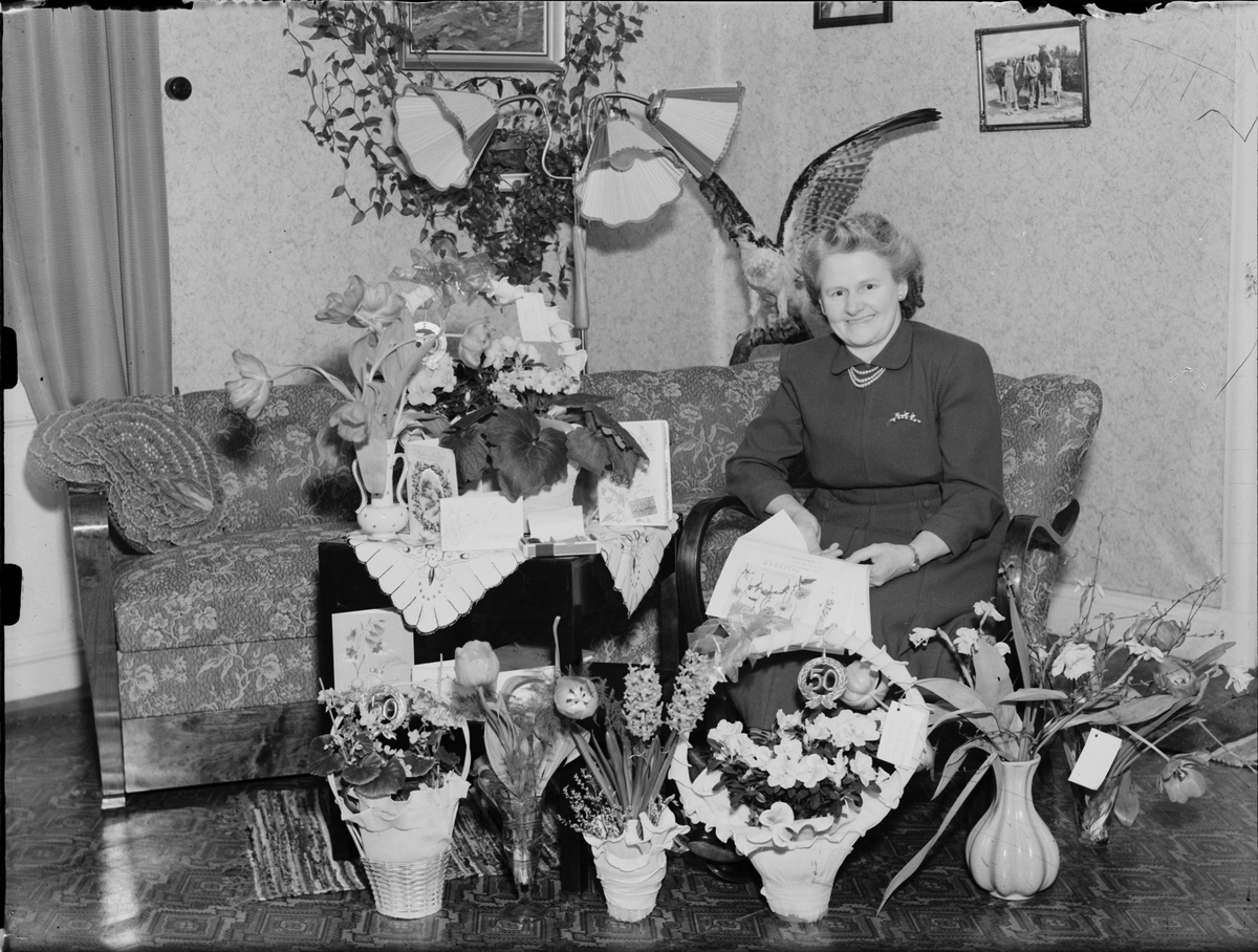 Kvinna i hemmiljö omgiven av blommor, Östhammar, Uppland,