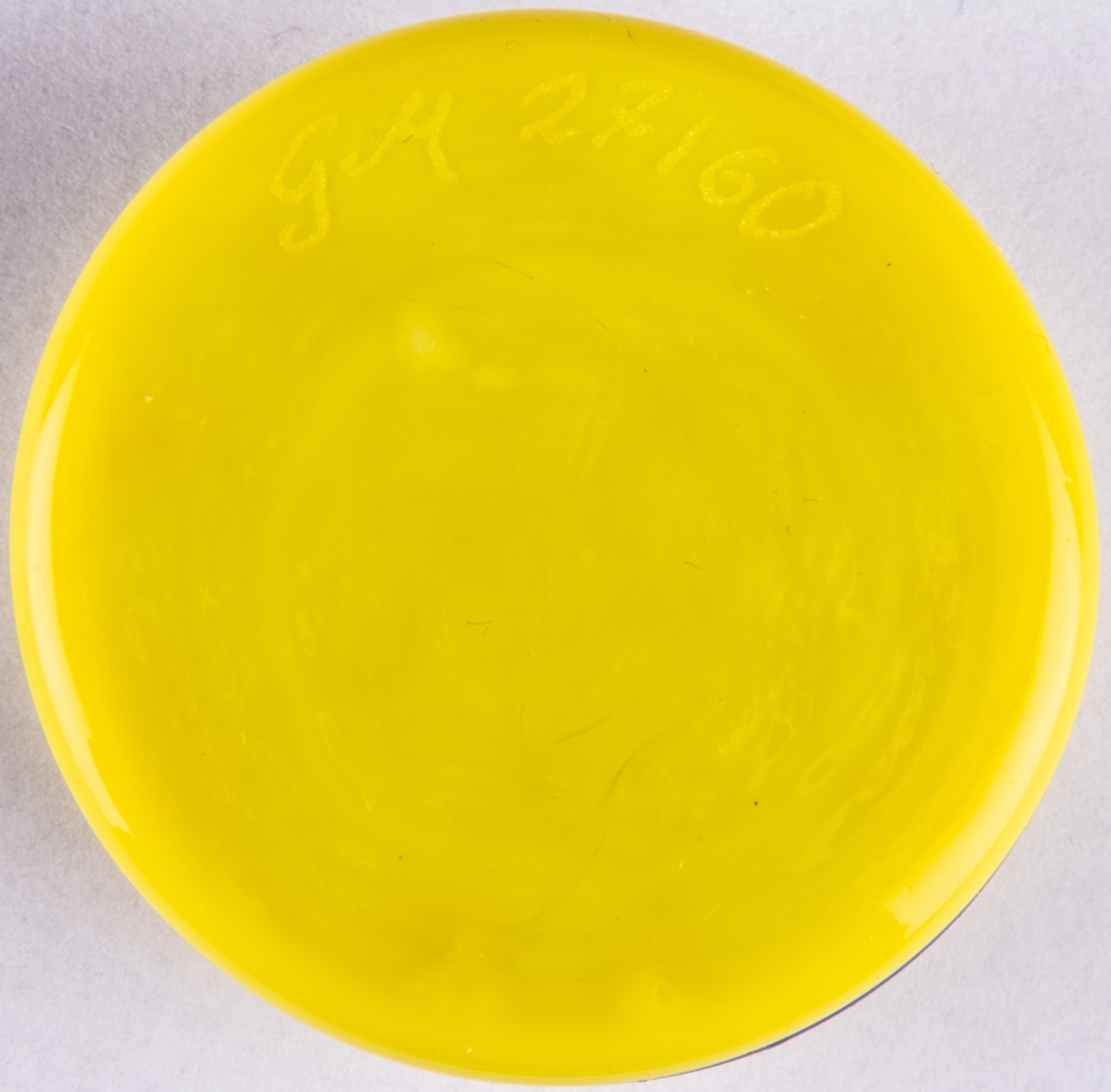 Brevpress, småkaka, i kristall. Uppbyggd av tre cirkelrunda hopfästade plattor i gult, blått, gult. Orrefors glasbruk, design Gunnar Cyrén.