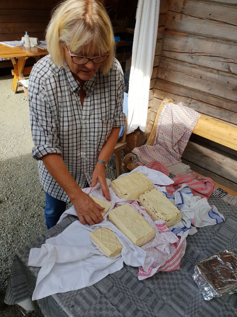 Margareta Meissner visar prov på olika ostar med olika kryddning. Västtjärnslindan, Gagnef, 2018.