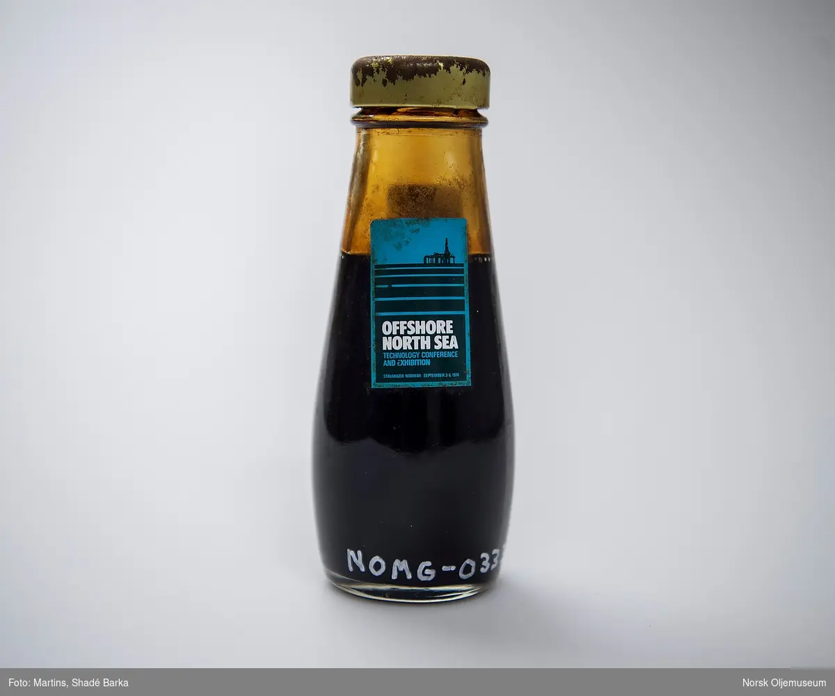 Oljeprøve fra Ekofisk oppbevart i en flaske med skrukork. På ene siden er merkelapp med Phillips Petroleums logo. På den andre siden er merkelapp med Offshore North Sea (ONS) 1974.