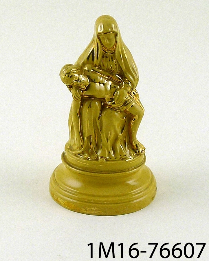 Figurin med pietà-motiv (ett tema för kristen konst som avbildar en sörjande Jungfru Maria vid sin döde sons kropp). Figurinen har gul glasyr och handmålade detaljer i guld.