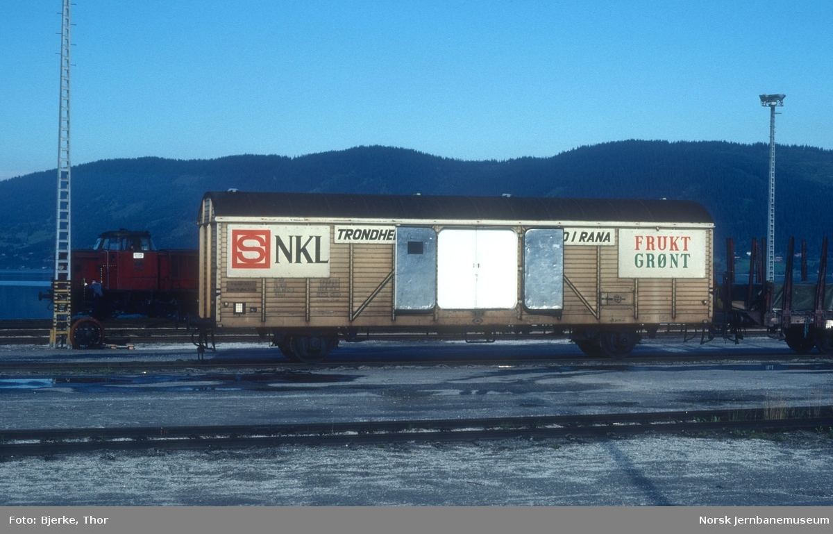 Isolert vogn litra Ibblps nr. 805 8012-3 med NKL-reklame på Mo i Rana stasjon