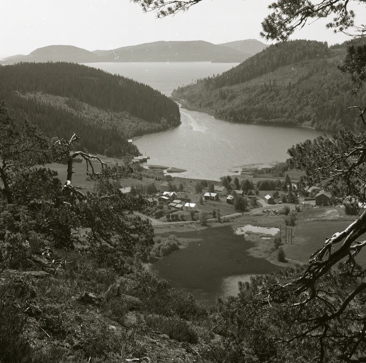 Utsikt över en dalgång med sjö, berg och byggnader i Nordingrå, 1974.