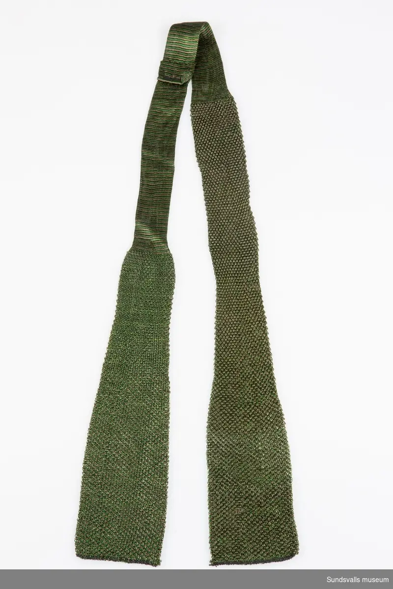 Grön- och brunmönstrad slips i maskinvävd konstfiber.