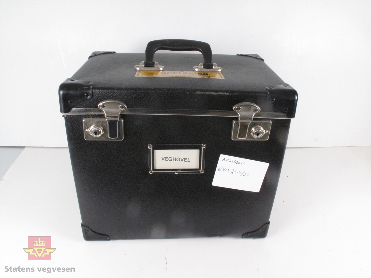 Én av seks kasser med opplæringsmateriell. Kassen består av informasjon om "Veghøvel". 
Kassen er svart og er laget av tykk kartong og kan låses med to "koffertlåser". Et håndtak på lokket.