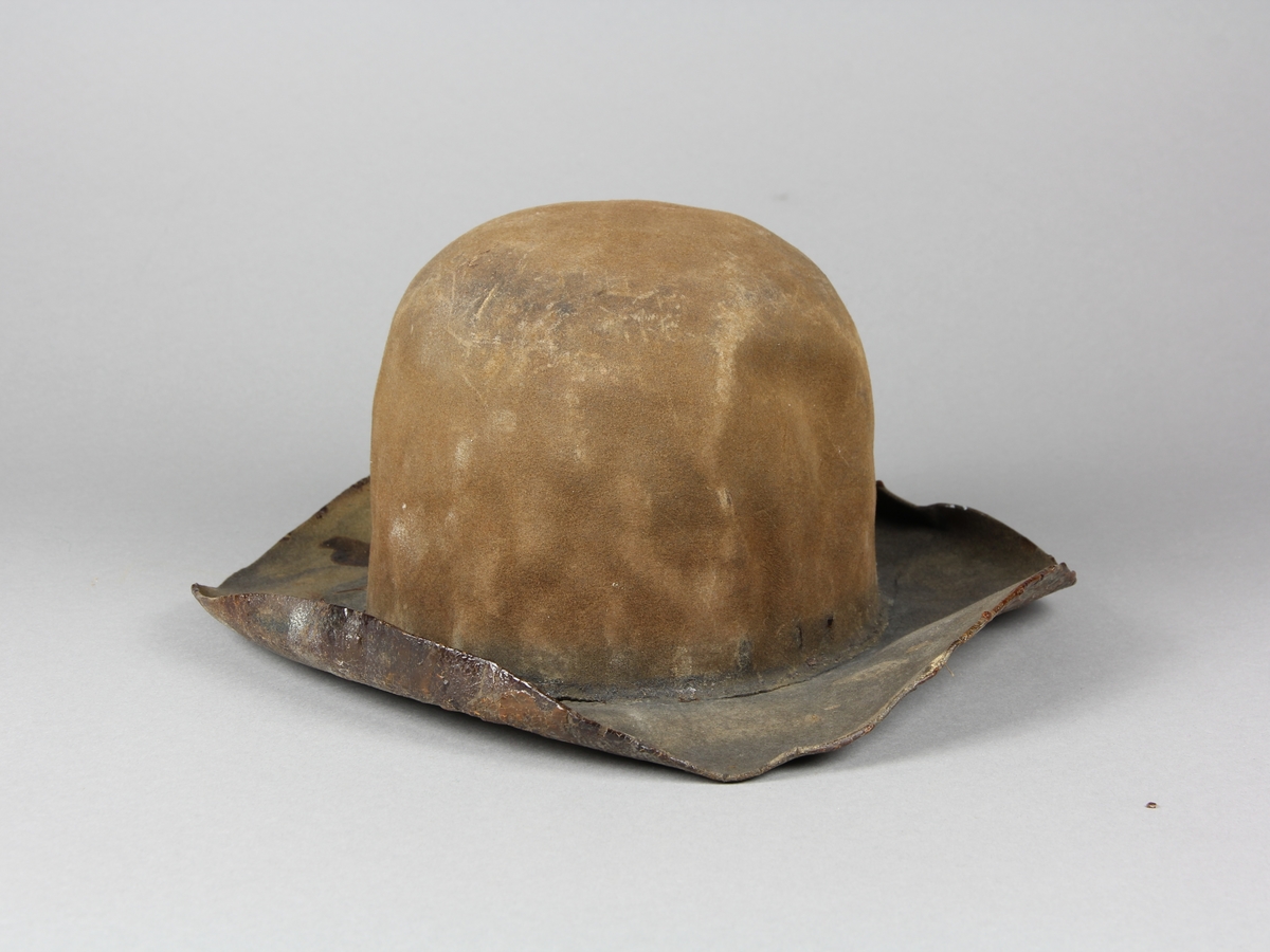 Hatt av brun filtad ull. Hatten har använts för filtering av schellack i snickerifabrik. Insidan av hatten är täckt med lager av intorkad schellack. Använd tillsammans med kruka SKAFOR.0017782A.