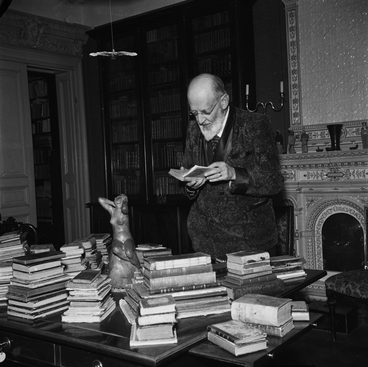 Professor Olof Östergren står vid ett skrivbord med böcker, Uppsala 1947