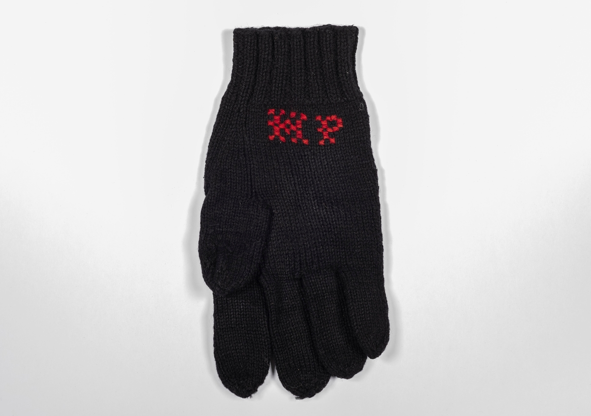 En svart strikket hanske med broderte initialer.