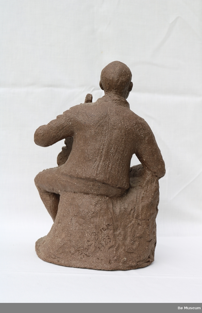 Statuen forestiller felespelaren Lars Fykerud sittande i folkedrakt mens han holder fela i venstre arm.