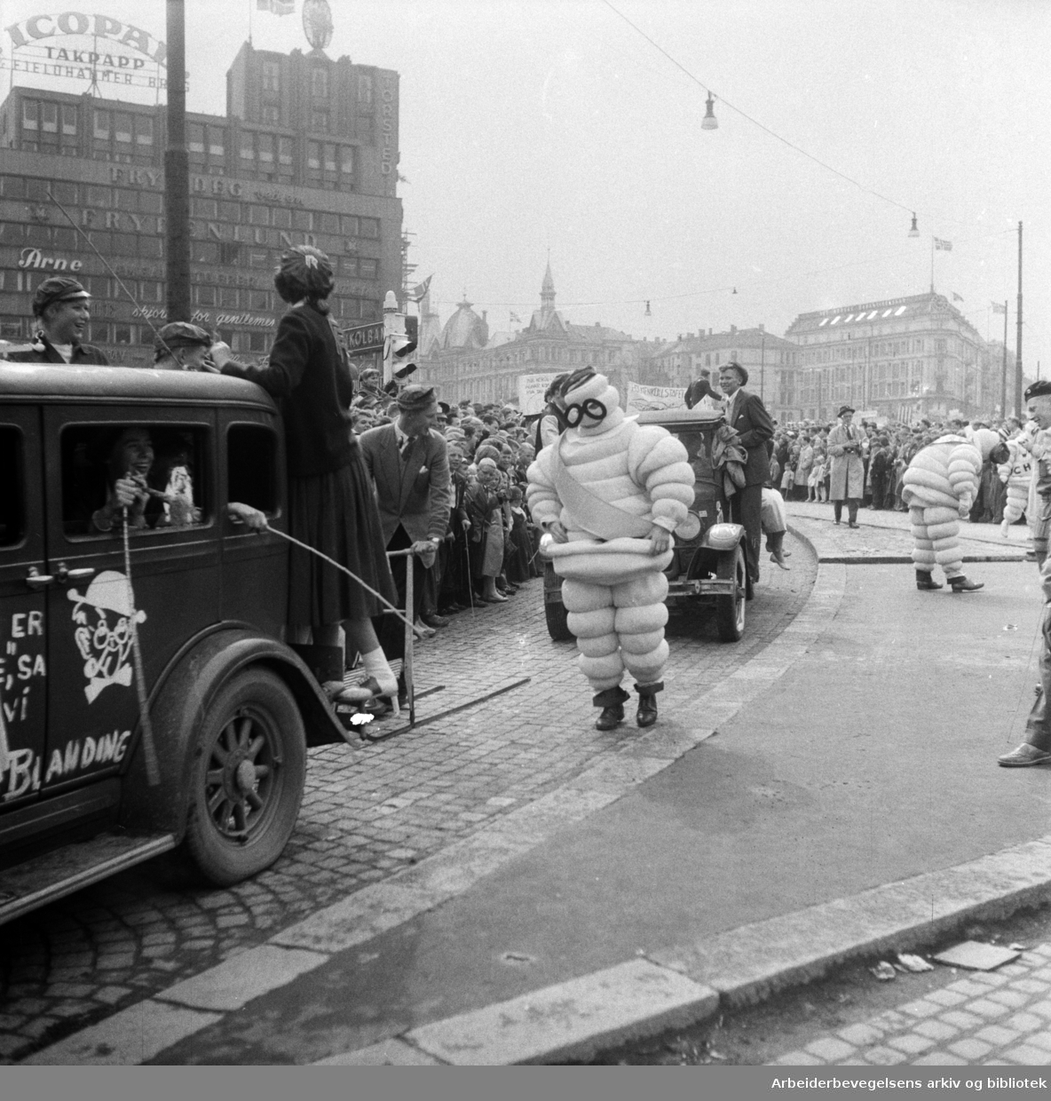 Russetoget. 17. mai 1957. Torstedgården og Victoria terrasse i bakgrunnen. Michelin-mannen. Monsieur Bibendum.