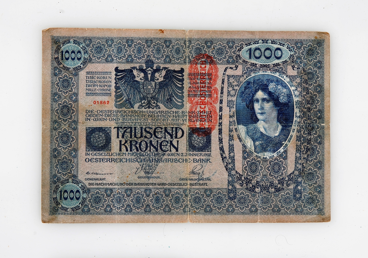 Stor 1000-kroneseddel fra Østerrike-Ungarn fra 1902. Vurdert hos Numisma mynthandel i Oslo til å ikke å noen verdi pga stort opplag. Visittkort derfra vedlagt. På seddelen er det er rødt stempel der det står Deutchösterreich.