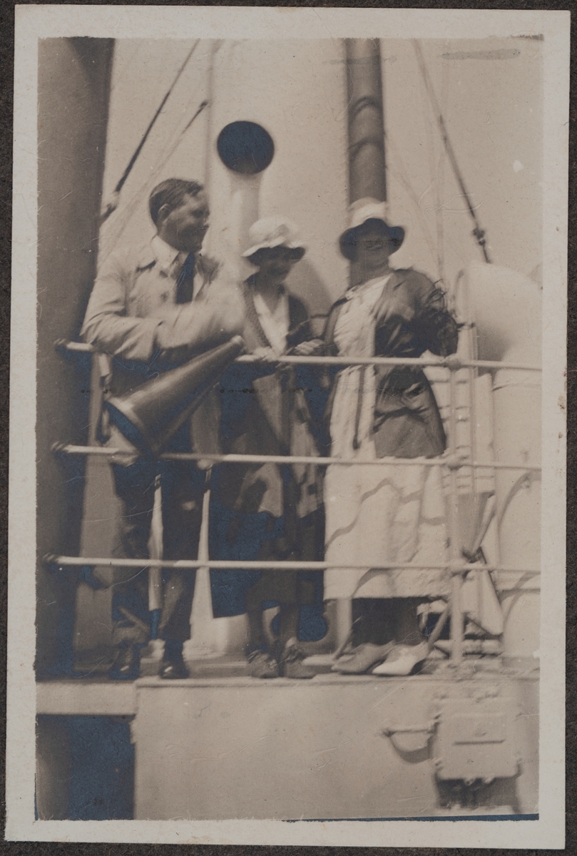 En man samt två kvinnor som står ute på däck.
Bildtext: "Tjänaren Grundberg!"