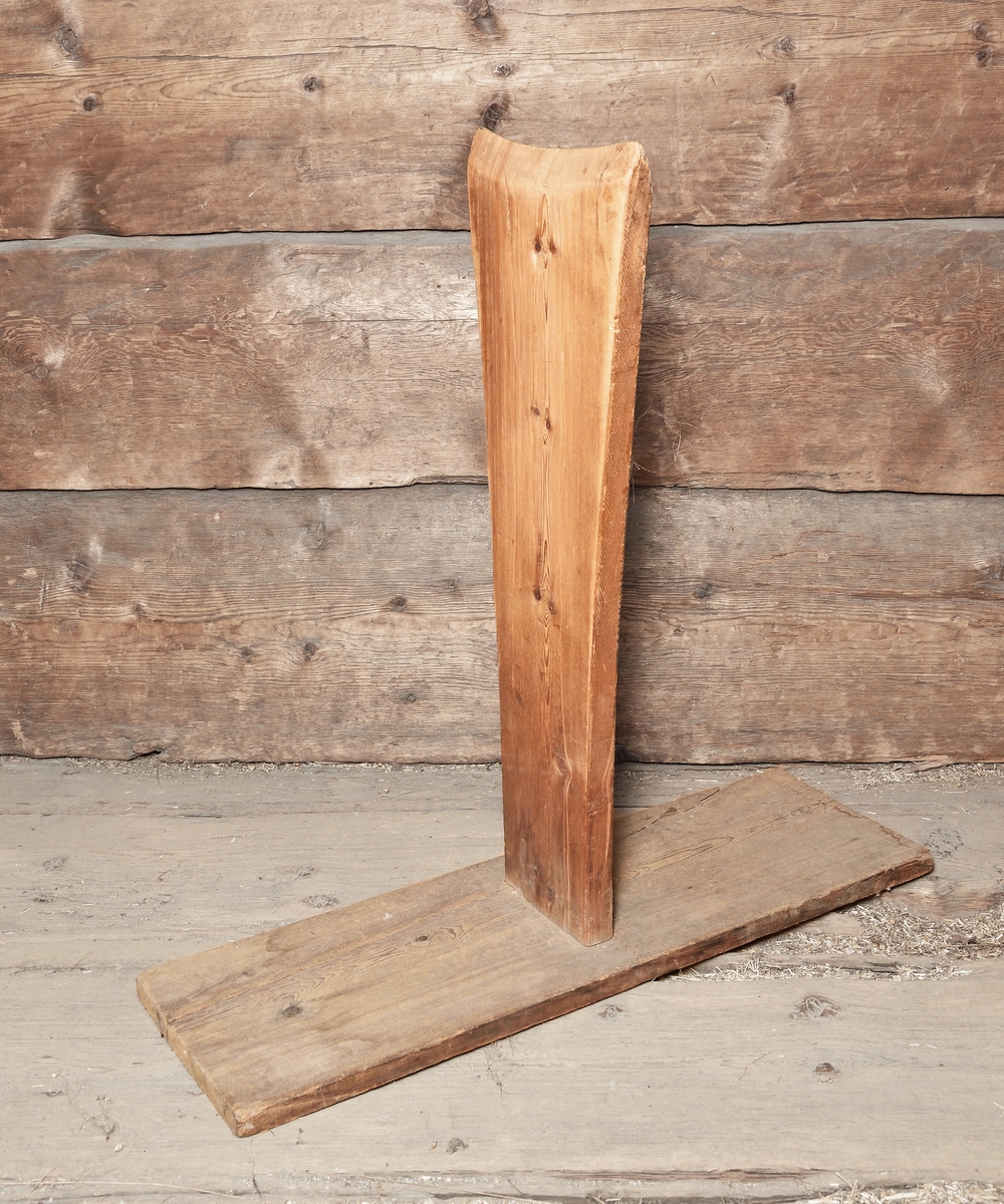 Skäktstol, skäktfot, tillverkad av trä. Rektangulär fot, vinkelställd bräda, upptill spetsig.