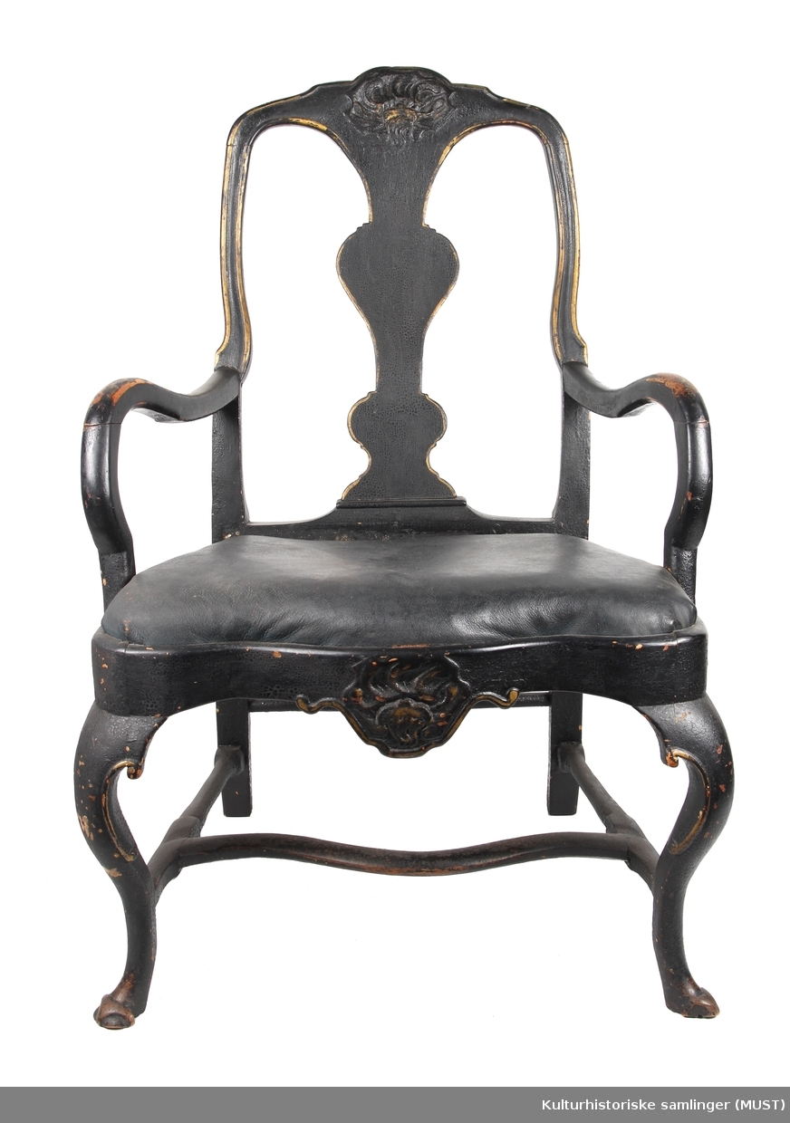 Sortmalt stol med armlener. 
Toppstykke og sarg har  usymmetrisk skjellformet ornament. 
Svungne bein, sarger og armelen. 
Symmetrisk kontuert ryggbrett.  Setet har sekundært trekk av lær.