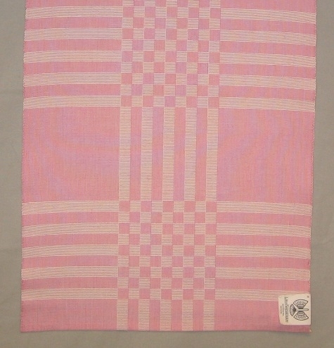 Rutig löpare, två stycken, vävd i varprips en i rosa och en i svart. Det är blekt och färgat tvåtrådigt bomullsgarn i varpen och blekt tvåtrådigt bomullsgarn i inslaget.
De smala fållarna är tråcklade.

Den rosa löparen är märkt R15:1 och den svarta R15:2.

Löparen med modellnamn Golv är formgiven av Ann-Mari Nilsson och tillverkad av Länshemslöjden Skaraborg. Den finns med  på sidan 38-39 i vävboken Inredningsvävar av Ann-Mari Nilsson i samarbete med Länshemslöjden Skaraborg från 1987, ICA Bokförlag. Se även inv.nr. 0001-0014,0016-0040.