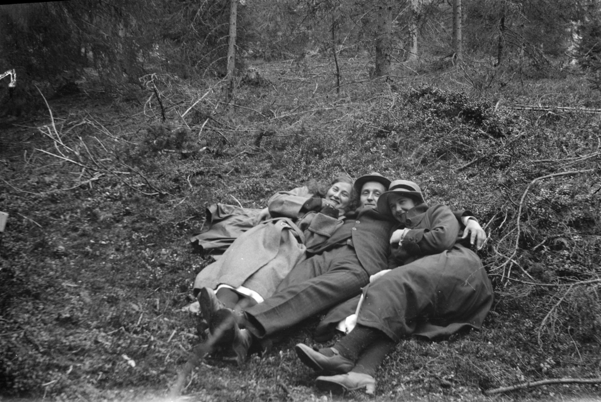 Muligens fotografen som ligger i gresset med en dame på hver side.