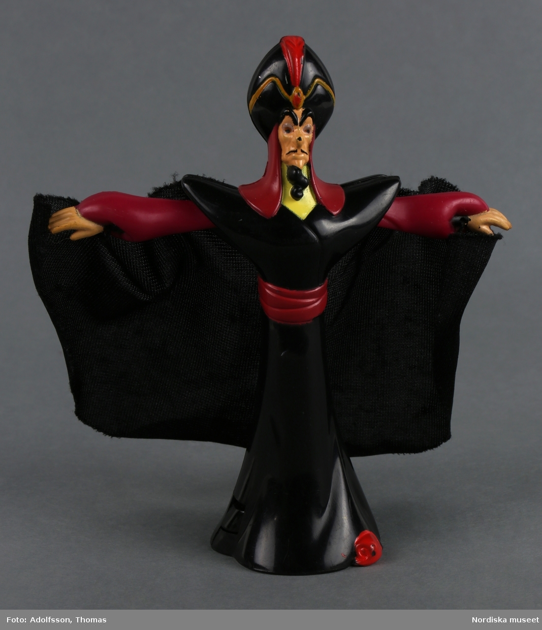 Mekanisk leksak som föreställer den maktlystne storvisiren Jafar. Han är klädd i en svart och vinröd kaftan, turban och slängkappa. Han har skägg och svarta ögonbryn. Armarna är rörliga. Om man trycker på mekanismen fälls armarna ut.