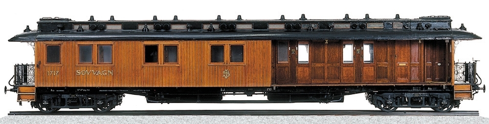 Modell av sovvagn Litt Ao1 Nr 1717, i skala 1:10 med brun teakpanel och svart tak.
Vissa detaljer är tillverkade av mässing. Vagnen är försedd med lanternin och grindar. Boggier. Sittplatser i brunt läder. Liggplatser täckta med grå filt. Vita gardiner i vissa fönster.