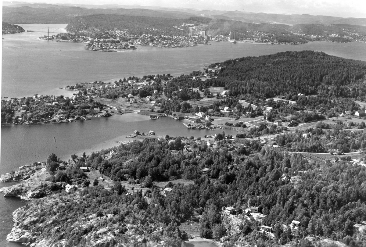 Flyfotoarkiv fra Fjellanger Widerøe AS, fra Porsgrunn Kommune. Sandøya med Brevik i bakgrunnen  . Fotografert 27.07.1963 av Edmond Jaquet