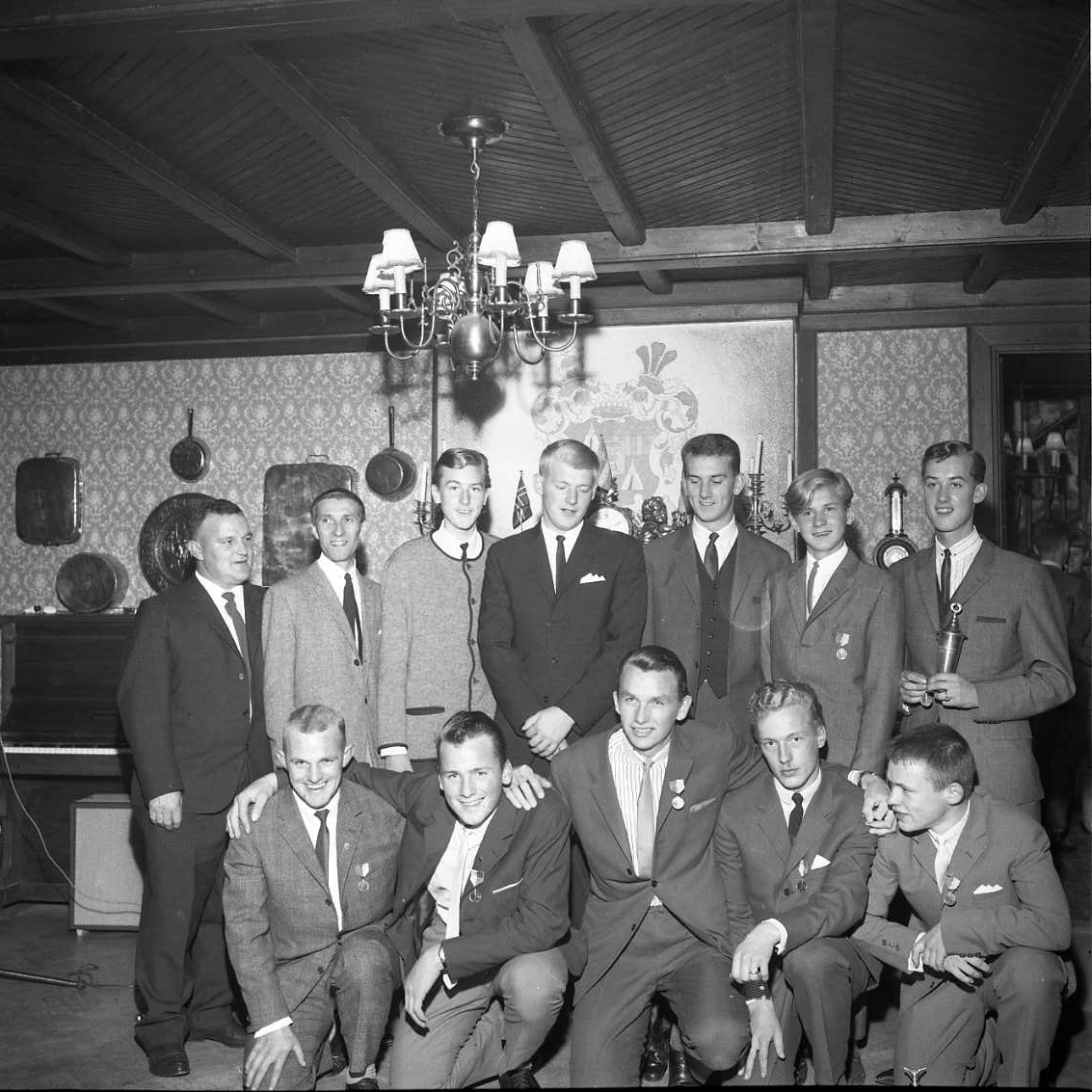Gruppbild med tolv unga män, några med medalj på bröstet andra med pokal i händerna. Längst fram till höger sitter möjligen Lars-Göran Andersson. Fotografi i samband med årsmöte för Gränna AIS.