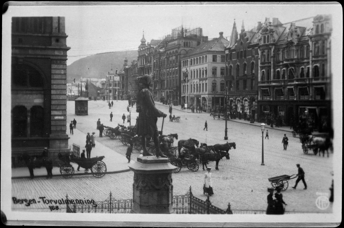 Närmast i bild ses staty av Ludvig Holberg på Torvalmenning i Bergen. Bilden är tagen före branden 1916.