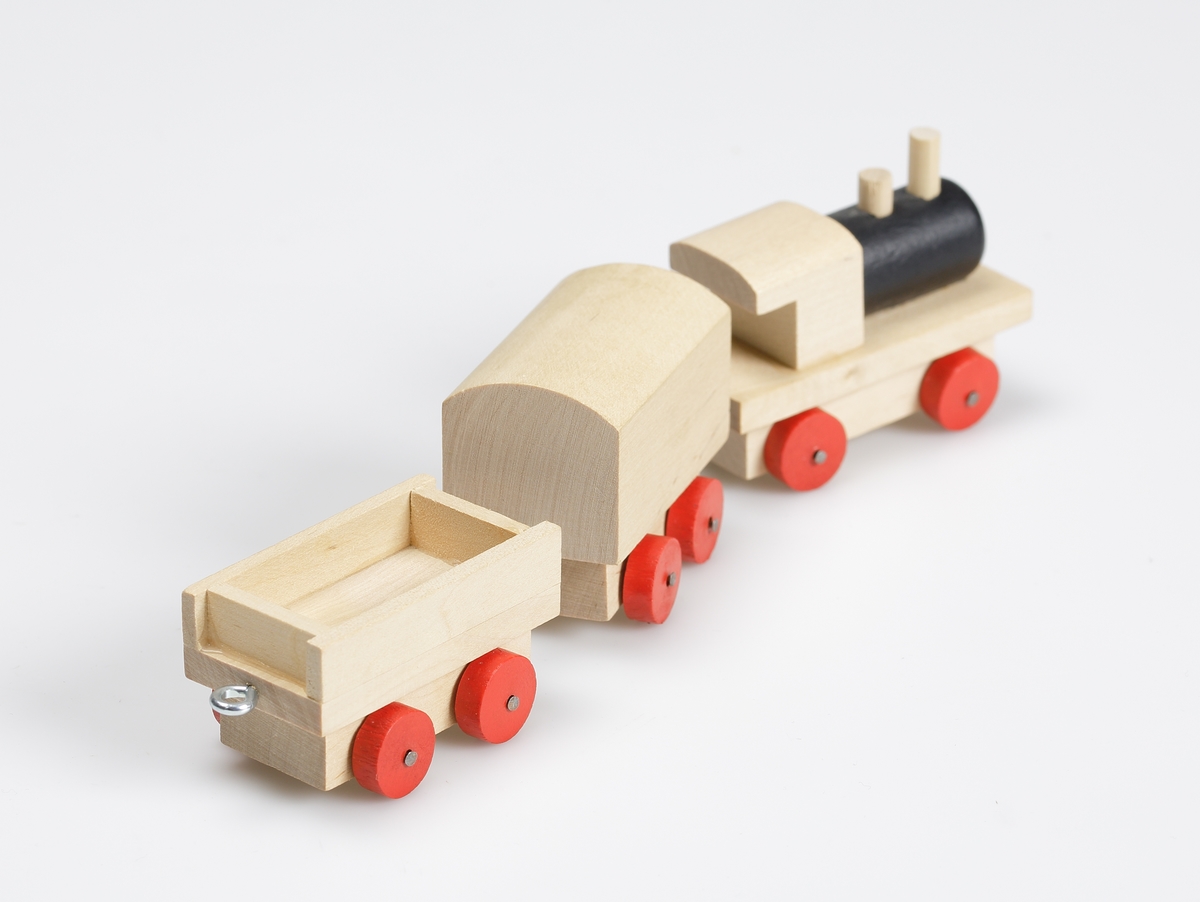 Leksakståg, av omålad björk. Hjulen är rödmålade, ångpannan är svart. Tåget består av lokomotiv med två vagnar. En vagn är täckt och en är öppen. Kopplingarna mellan vagnarna består av metallkrokar. Tåget är gjort efter gammal förebild.

Inskrivet i huvudkatalog 1981.